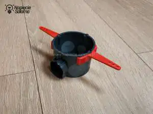 Uchwyty montażowe E104 zamontowane na pojedynczej puszce. Uchwyt E104 montuje się do ściany za pomocą gwoździ.
